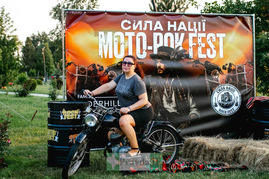 Жінка на мотоциклі біля банера MOTO-ROK FEST
