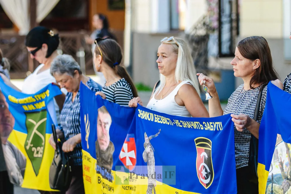 Жінки тримають прапори на памʼятному мітингу