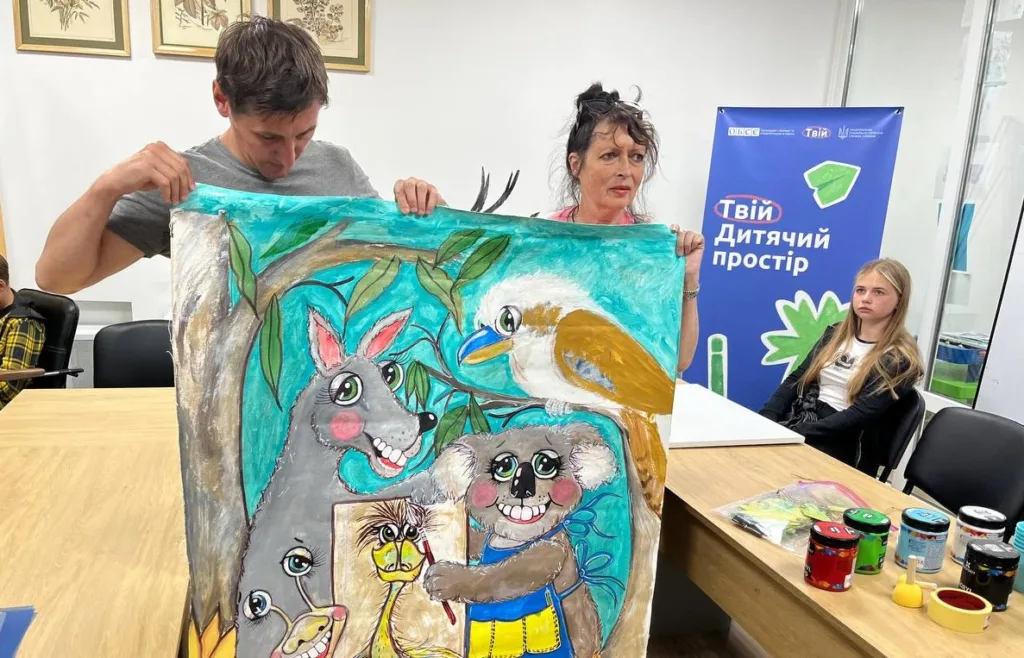 Люди показують дитячий малюнок із тваринами.