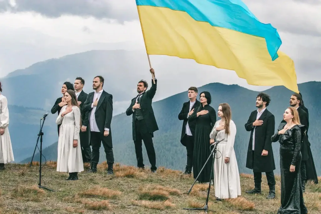 Люди співають під українським прапором у горах