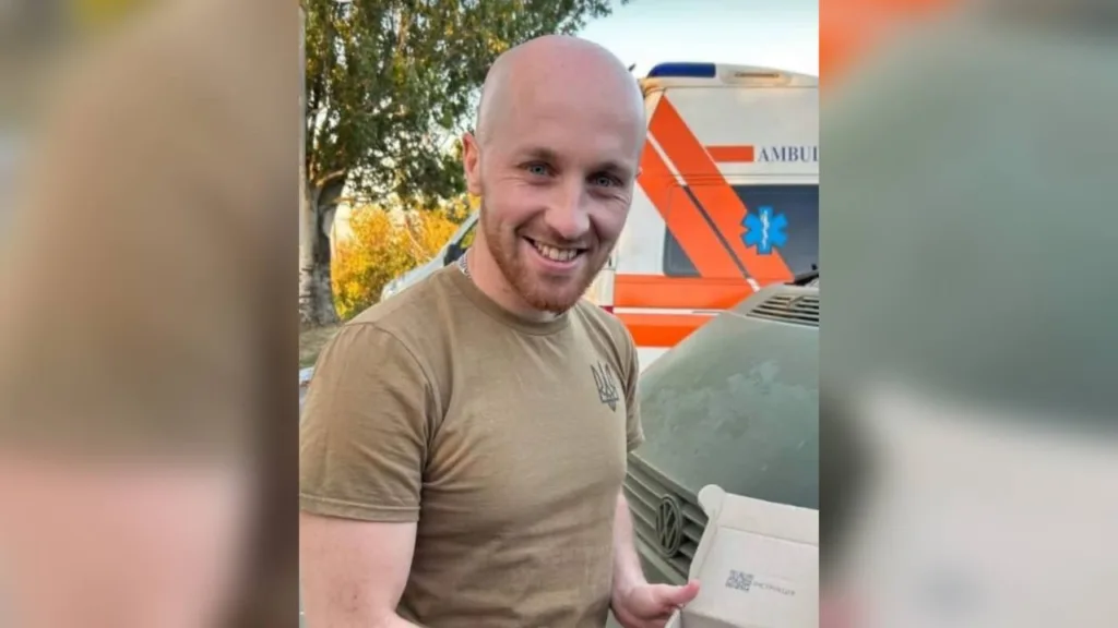 Чоловік посміхається біля автомобіля швидкої допомоги