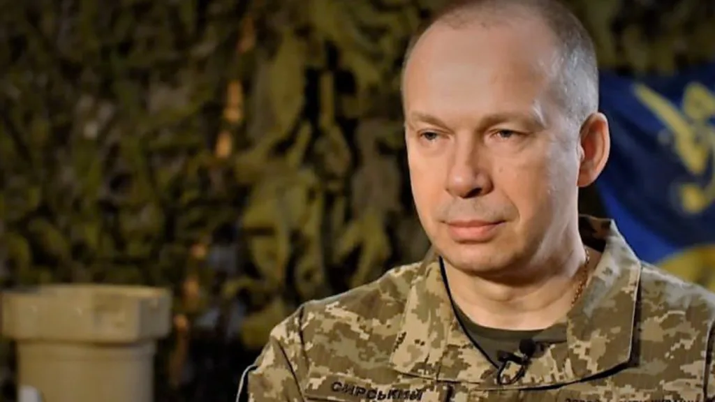 Український військовий у камуфляжі на фоні прапора