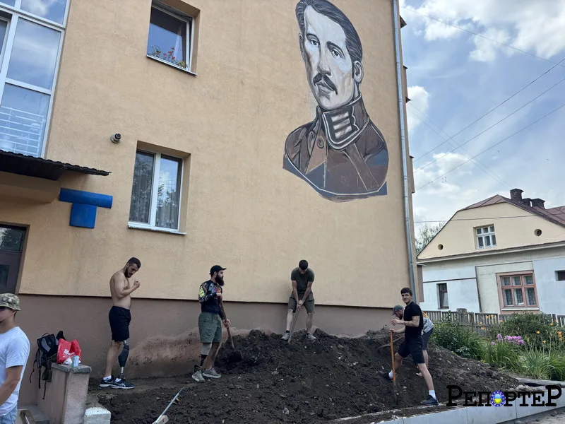 Люди працюють біля будівлі з великим муралом