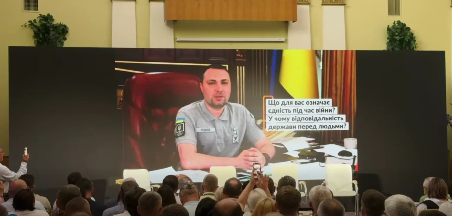 Виступ посадовця на великому екрані перед аудиторією