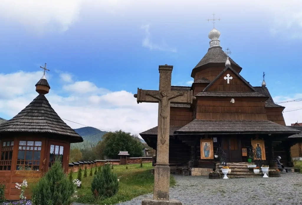 Дерев’яна церква в Карпатах з кам’яним хрестом