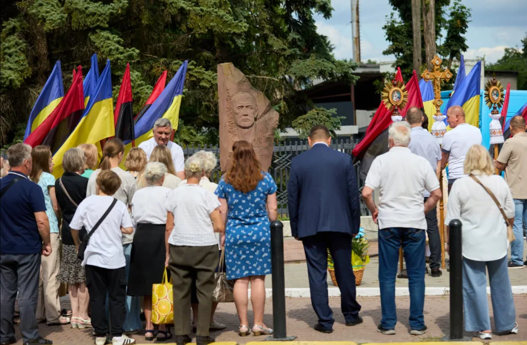 Люди біля пам’ятника з українськими прапорами