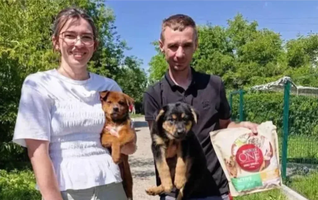 Двоє людей тримають щенят та корм Purina ONE