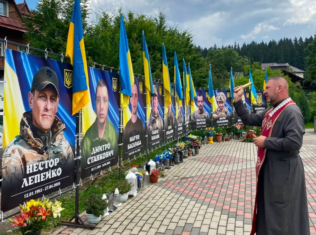 Священник молиться біля меморіалу загиблим героям України