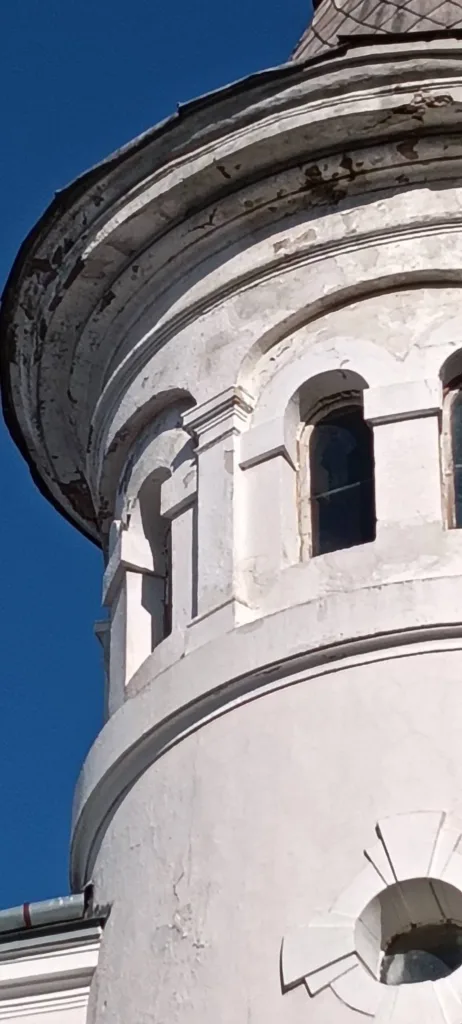 Стара біла церковна дзвіниця на тлі синього неба