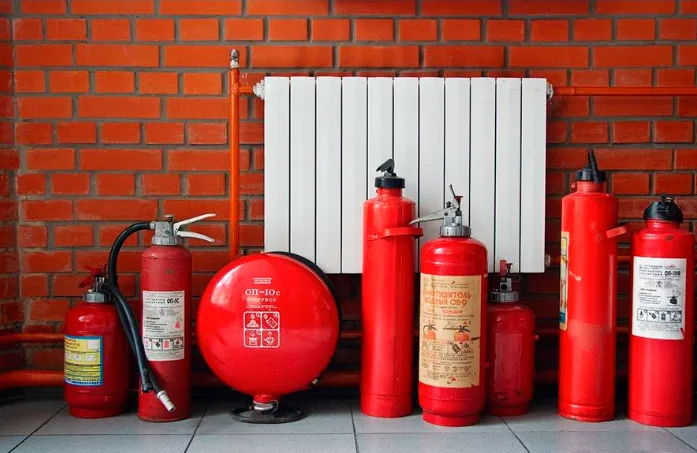 Червоні вогнегасники біля радіатора на цегляній стіні