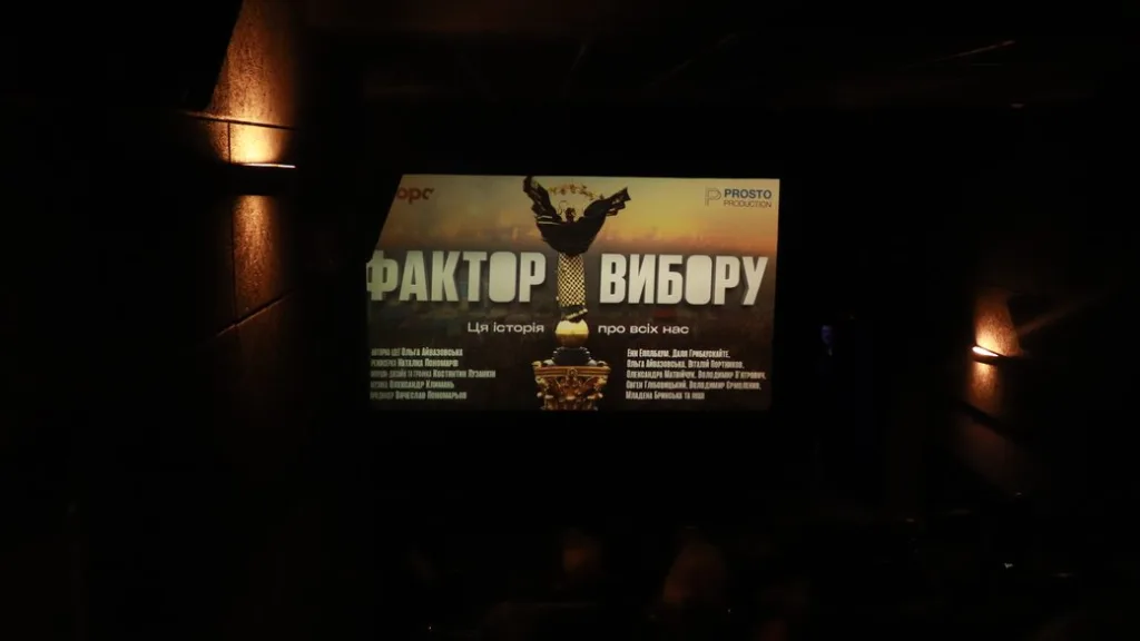 Екран у темному кінотеатрі з афішею «Фактор вибору»