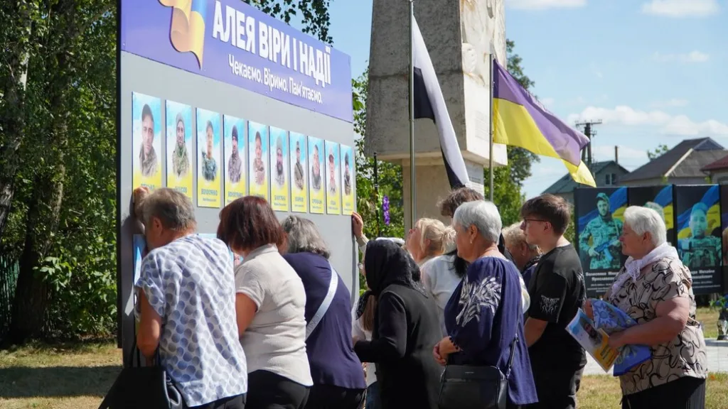 Люди біля стенда пам’яті полеглих військових