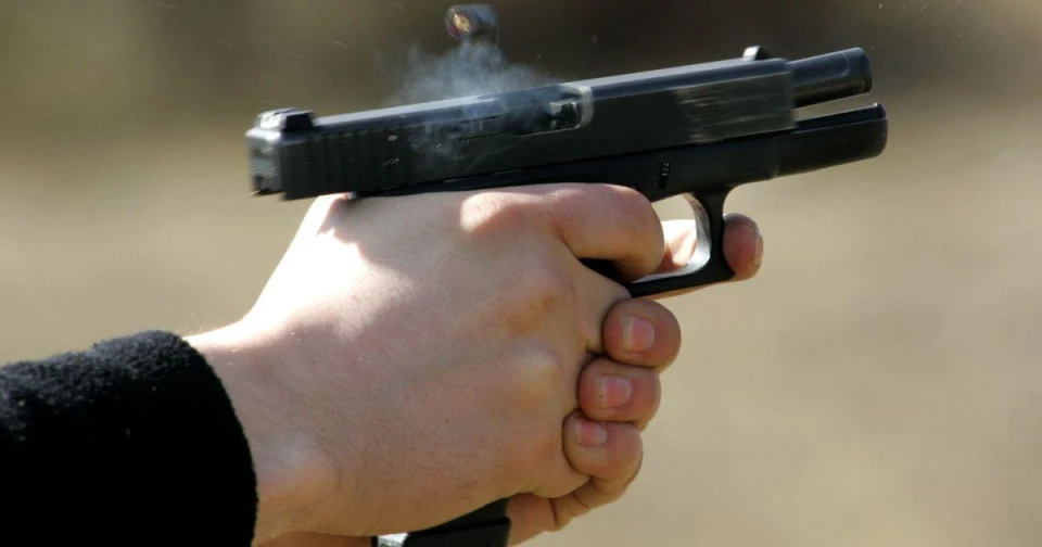 Рука стріляє з чорного пістолета, гільза в повітрі