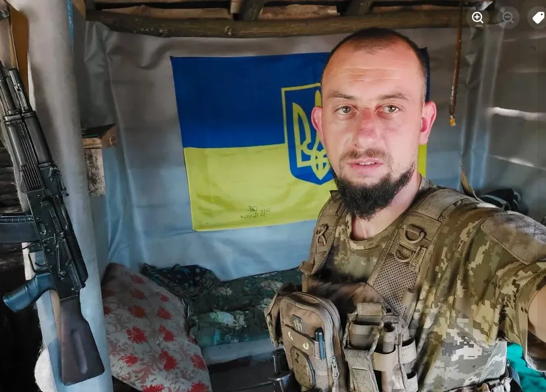 Український військовий у бліндажі біля прапора України