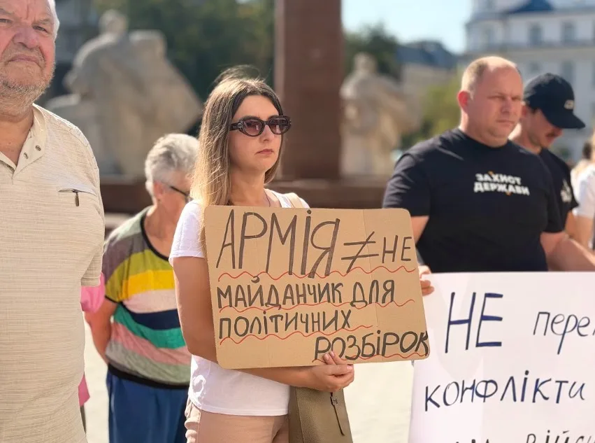 Жінка тримає плакат проти політизації армії