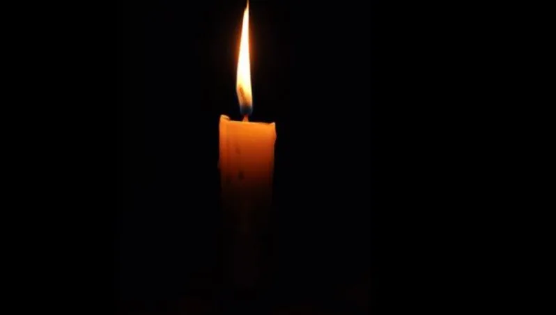 Самотня запалена свічка на темному тлі