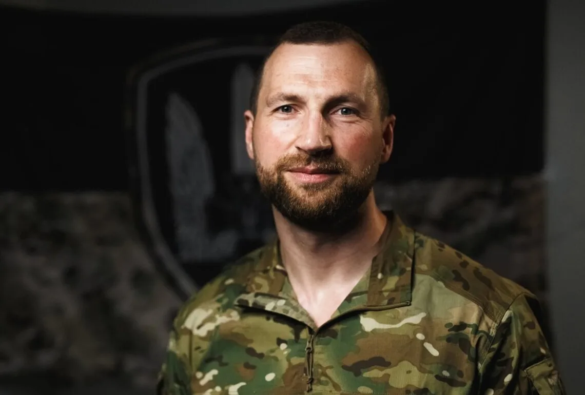 Бородатий військовий у камуфляжі дивиться в камеру