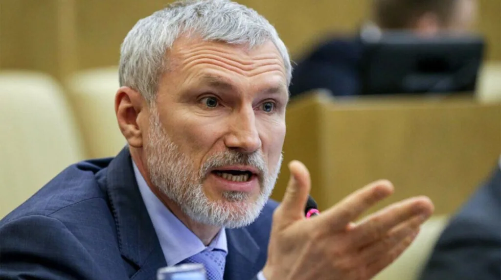 Сивий чоловік у костюмі жестикулює під час виступу