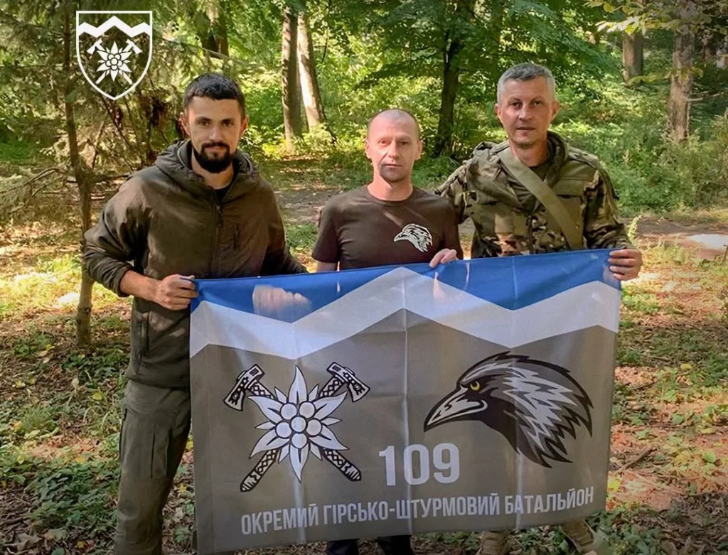 Троє військових із прапором 109-го батальйону в лісі