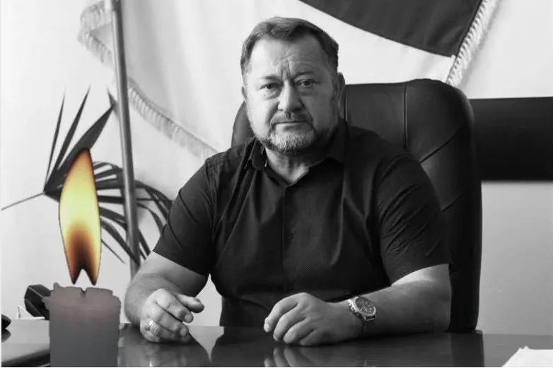 Чоловік сидить за столом поруч із запаленою свічкою