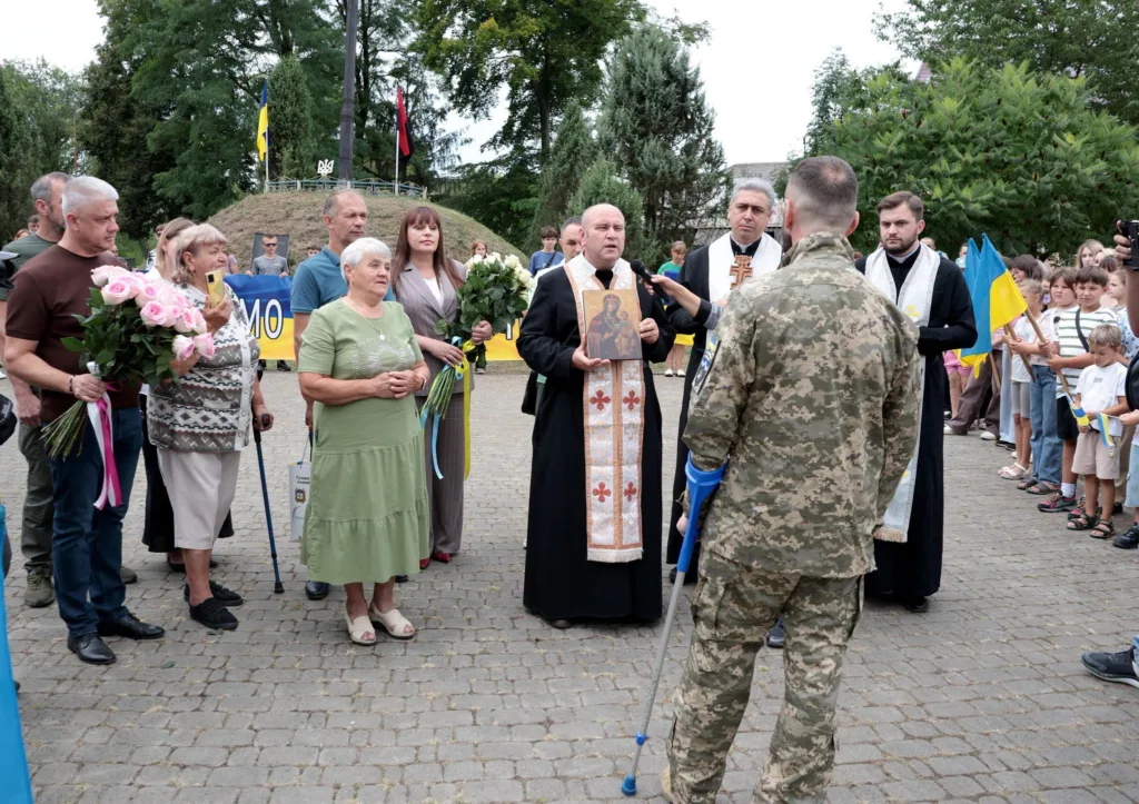 Військовий на милицях на меморіальній церемонії з прапорами