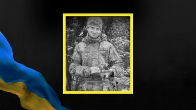 Чорно-білий портрет військового на тлі українського прапора