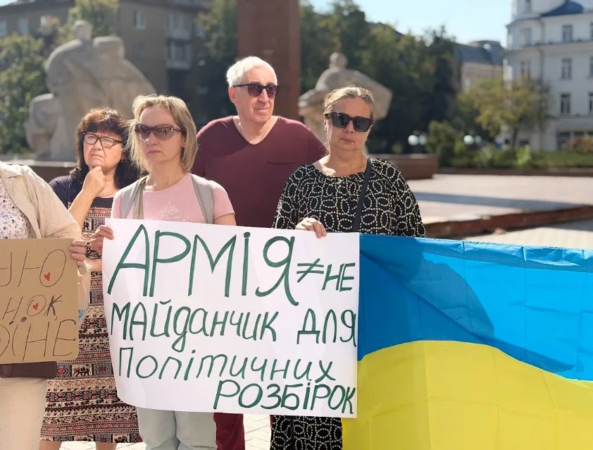 Люди з плакатом і українським прапором на мітингу