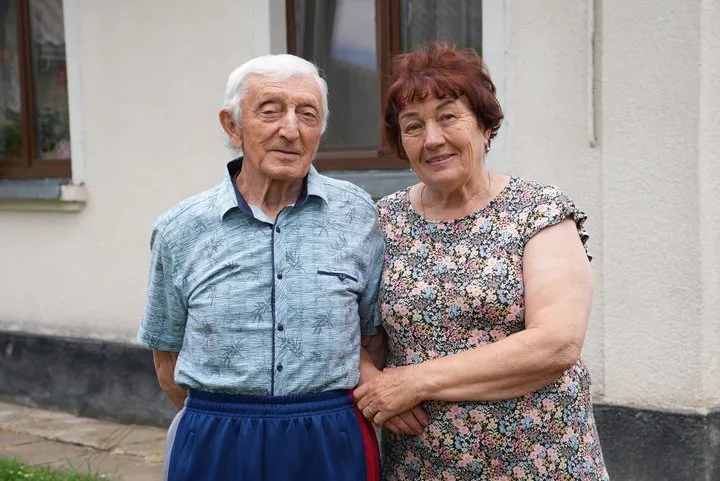 Літня пара стоїть біля будинку