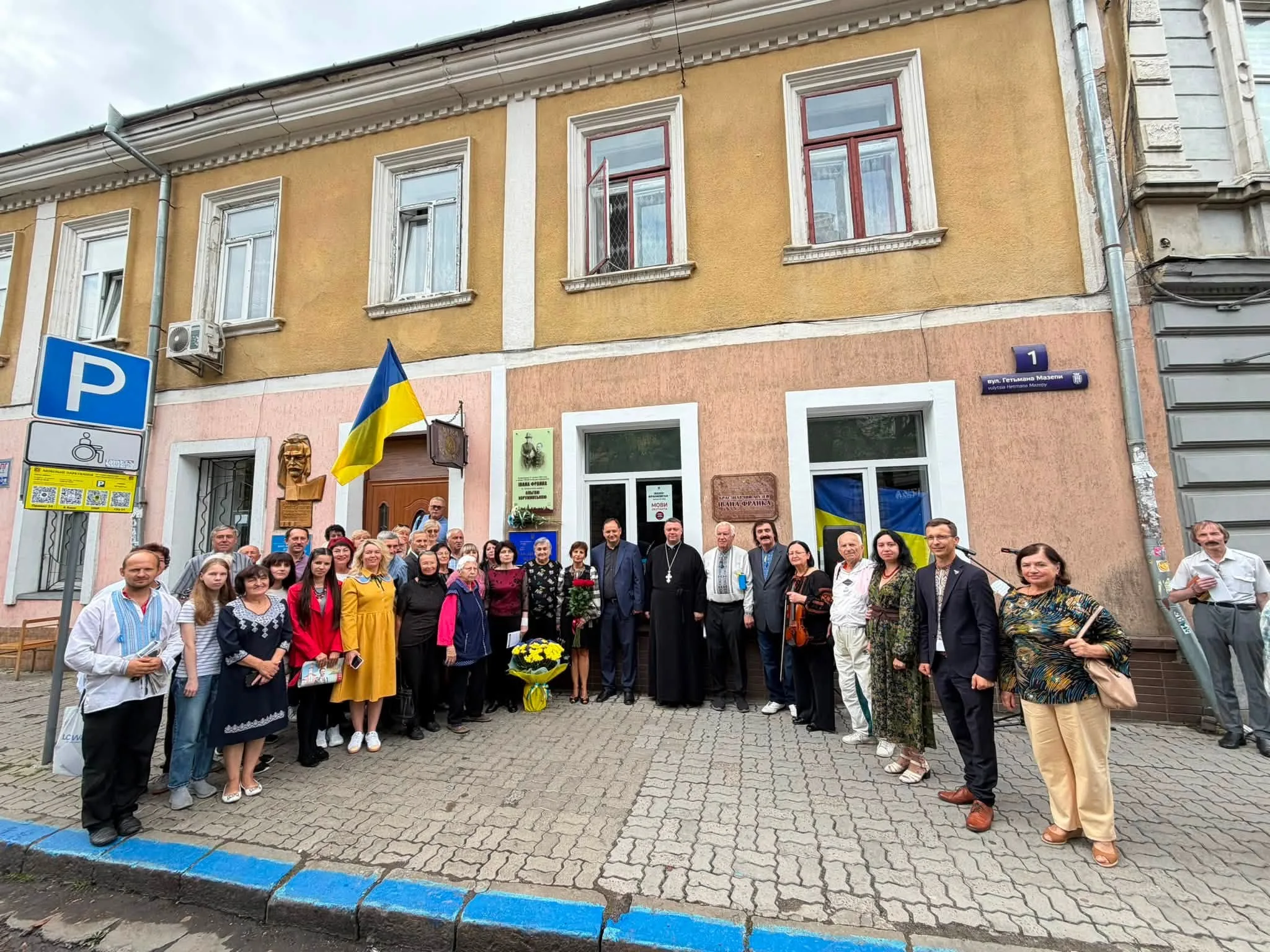 Група людей біля будинку з українським прапором