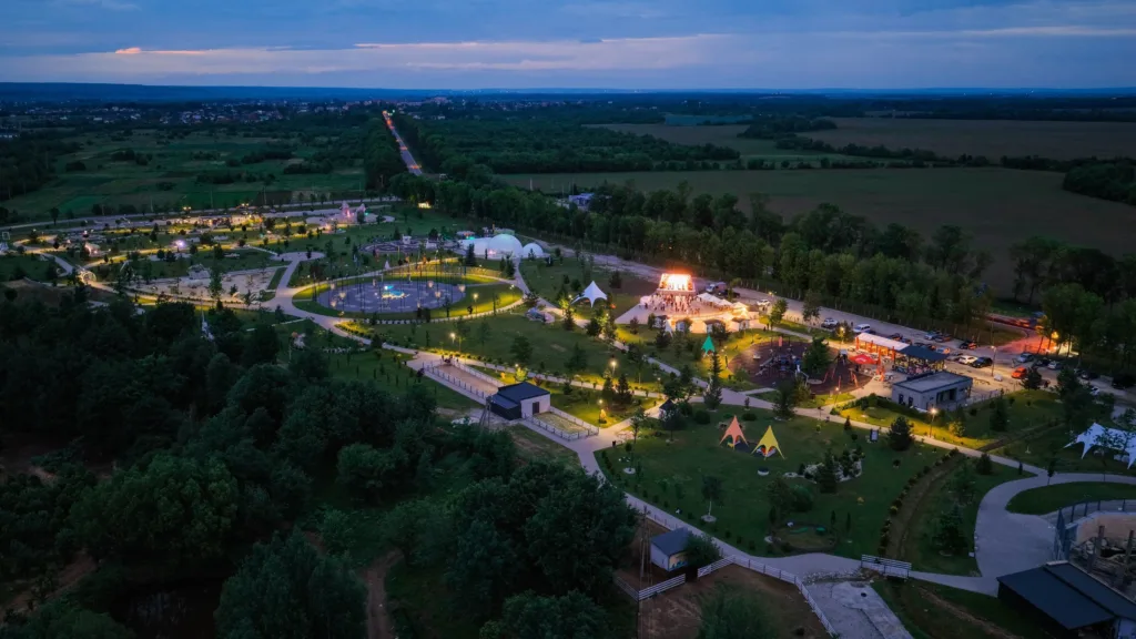 Вечірній парк із підсвіченими доріжками серед полів
