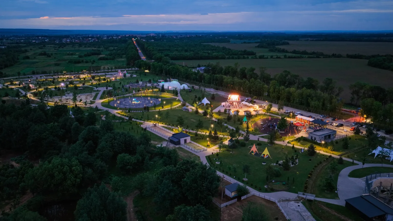 Вечірній парк із підсвіченими доріжками серед полів