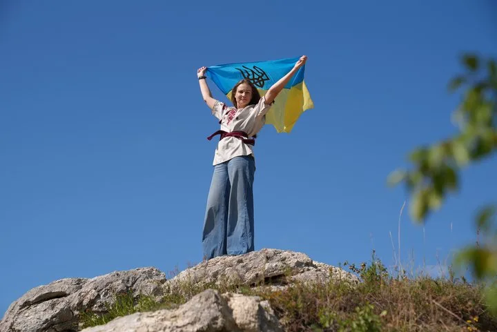 Жінка піднімає український прапор на скелі