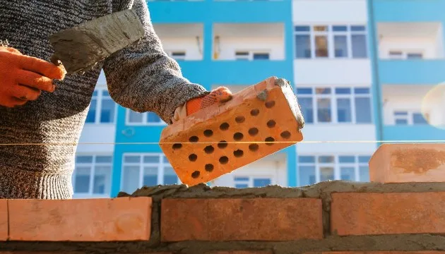 Муляр кладе цеглу на будівельний розчин