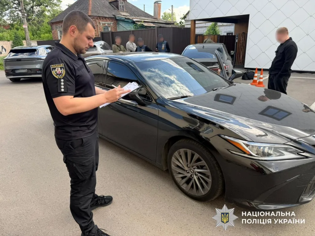 Поліцейський оформлює документи біля чорного автомобіля