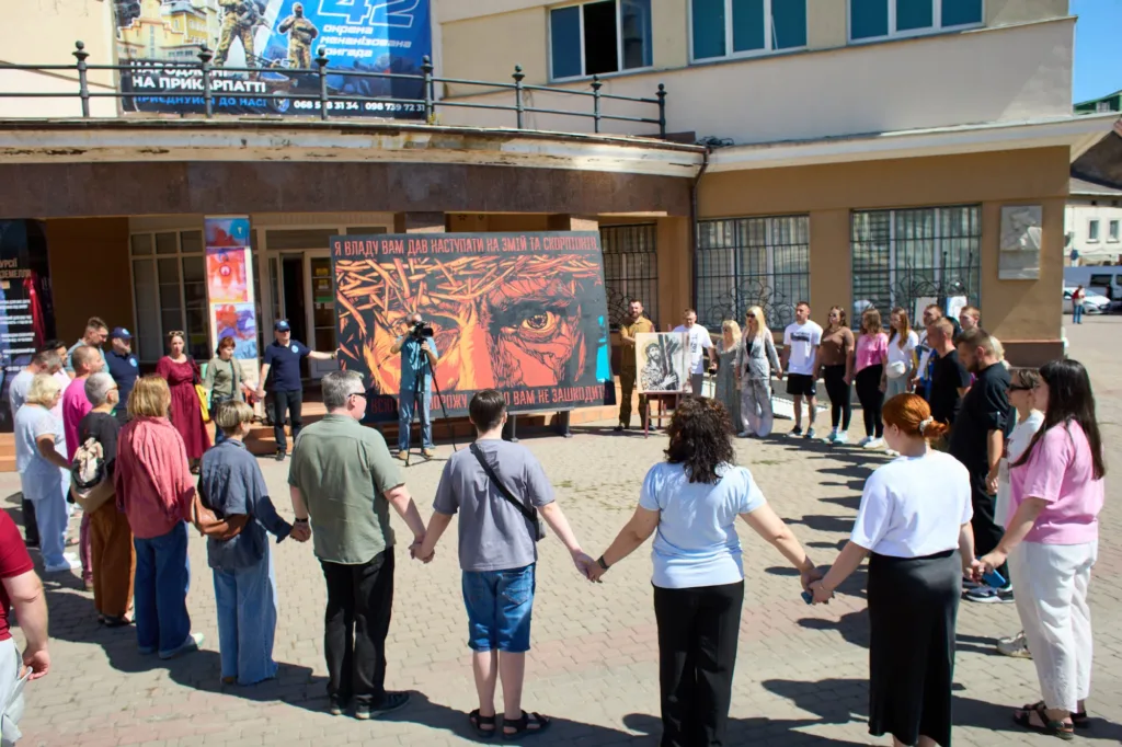 Люди тримаються за руки біля антивоєнної інсталяції