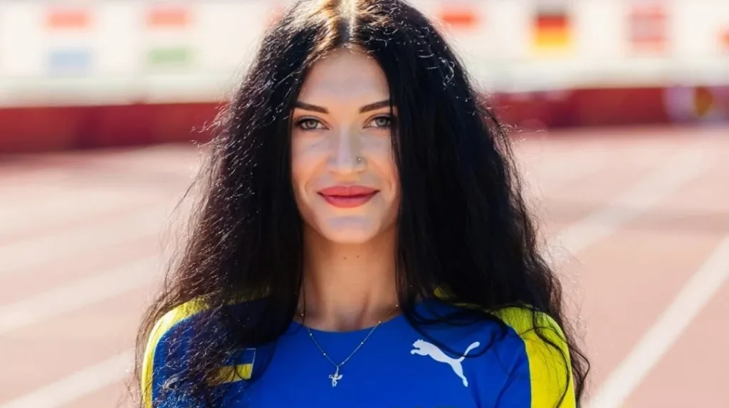 Усміхнена спортсменка у синьо-жовтій формі на стадіоні
