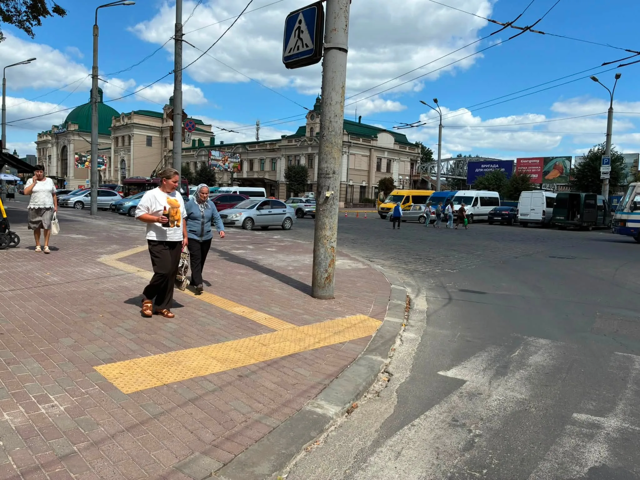 Пішоходи біля жвавої вулиці та історичної будівлі вокзалу
