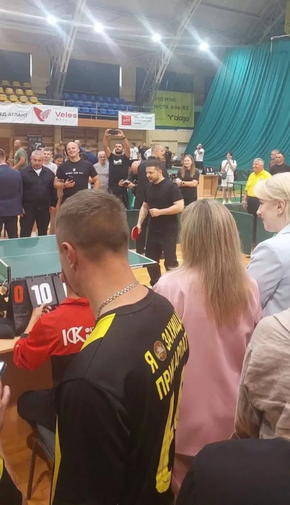 Чоловік грає в настільний теніс перед глядачами