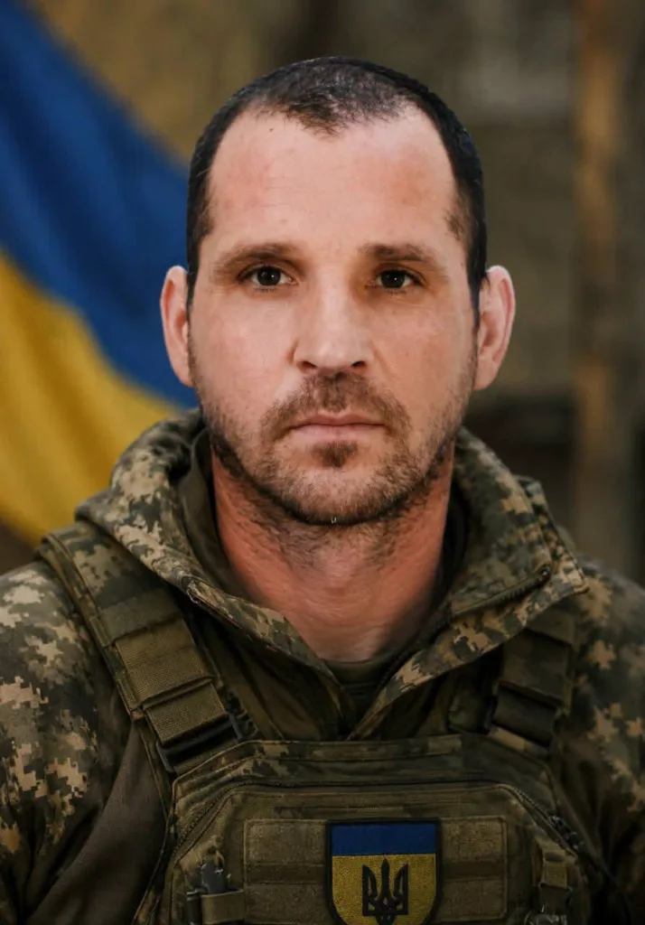 Портрет українського військового у камуфляжі на тлі прапора