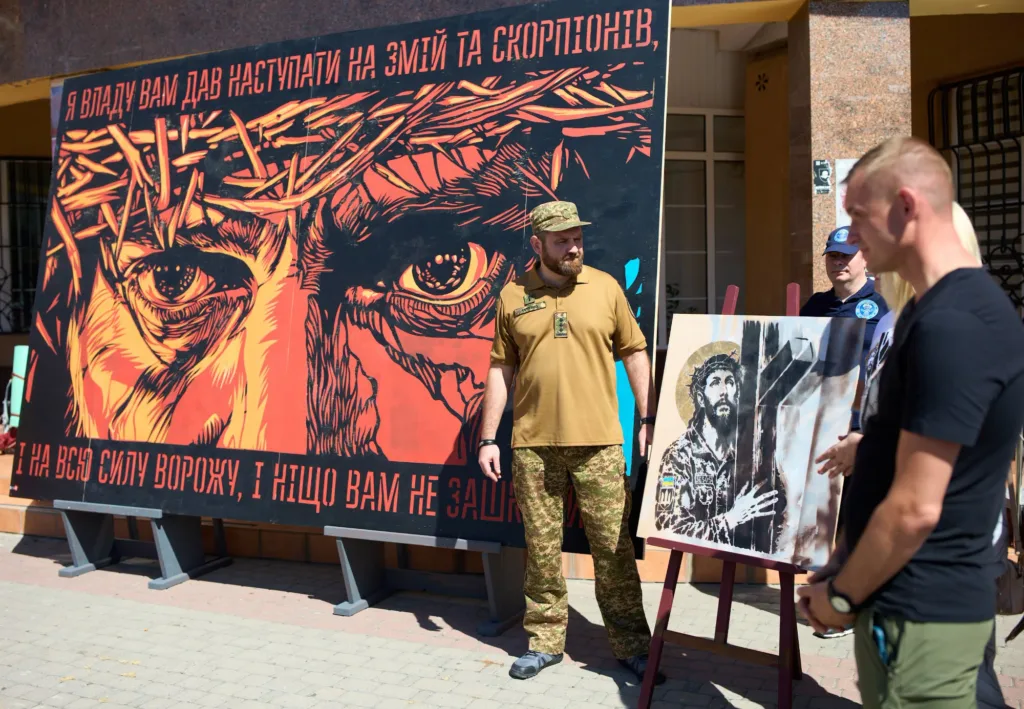 Військовий біля патріотичної виставки з портретом Ісуса