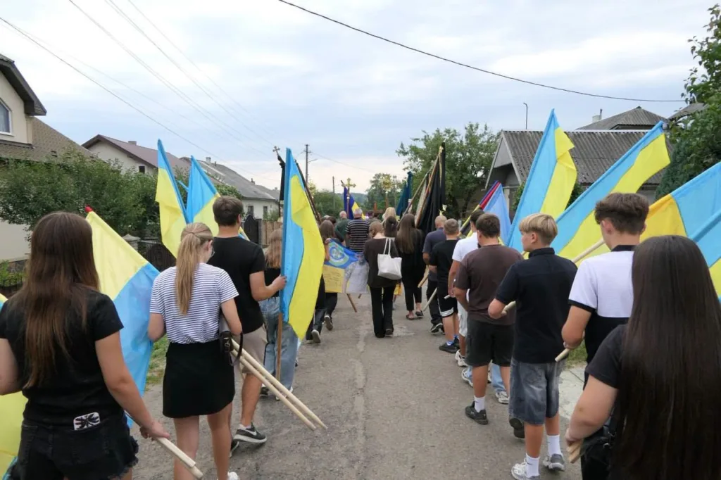 Люди несуть українські прапори вулицею села