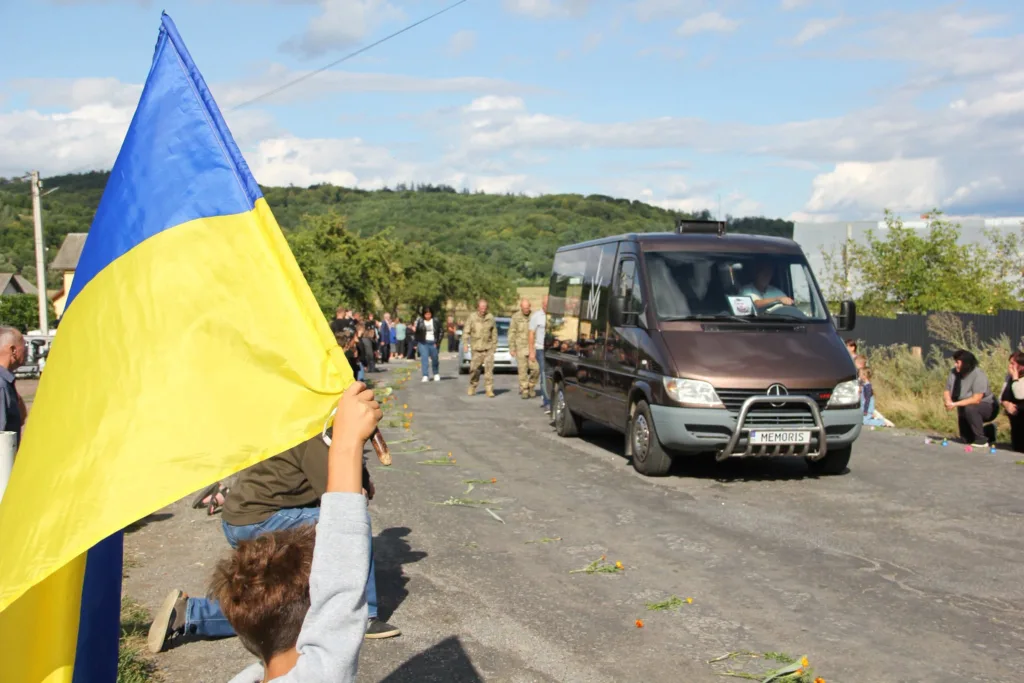 Український прапор біля катафалка на сільській дорозі