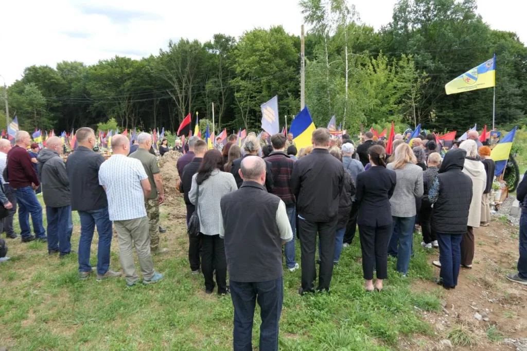 Люди з українськими прапорами на меморіальному зібранні
