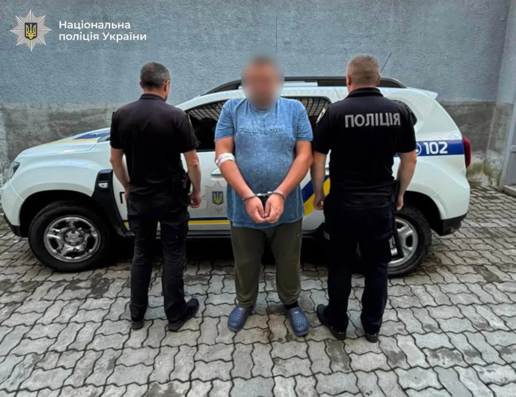 Затриманий у кайданках між поліцейськими біля службового авто
