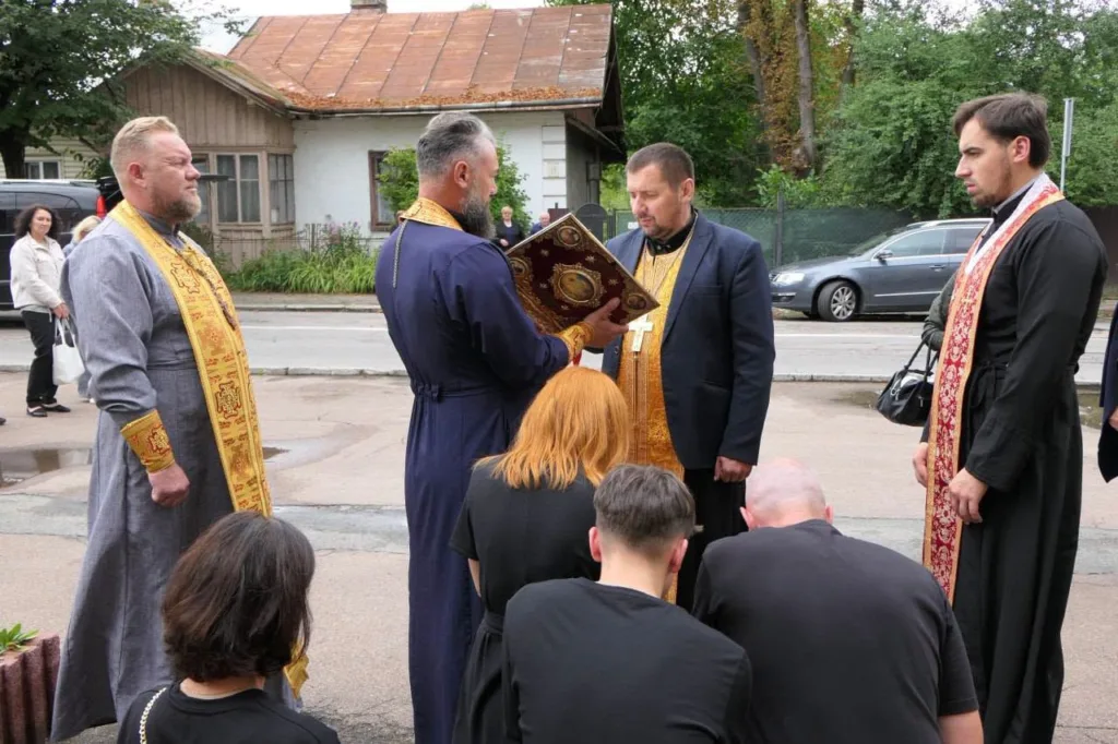 Священники моляться над людьми біля храму