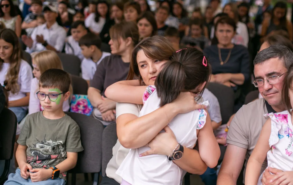 Мати обіймає доньку серед глядачів у залі