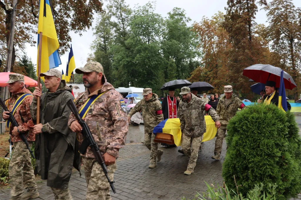 Військові несуть труну, вкриту українським прапором