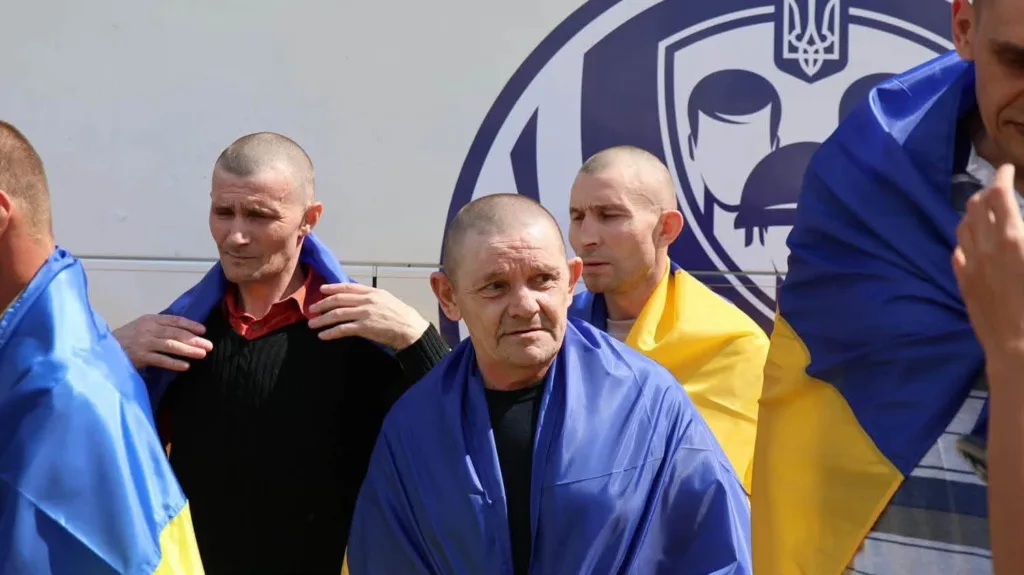 Чоловіки, загорнуті в українські прапори біля автобуса