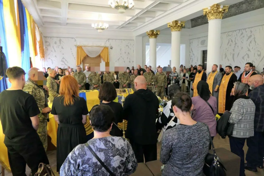 Церемонія прощання біля труни, вкритої українським прапором