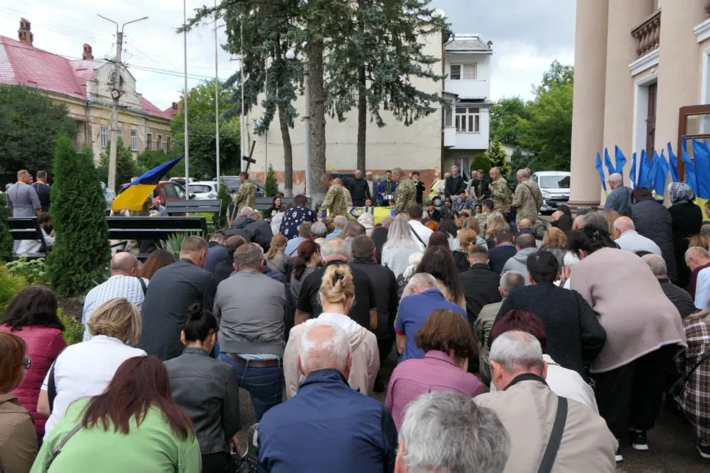 Люди схилилися в молитві біля українських прапорів